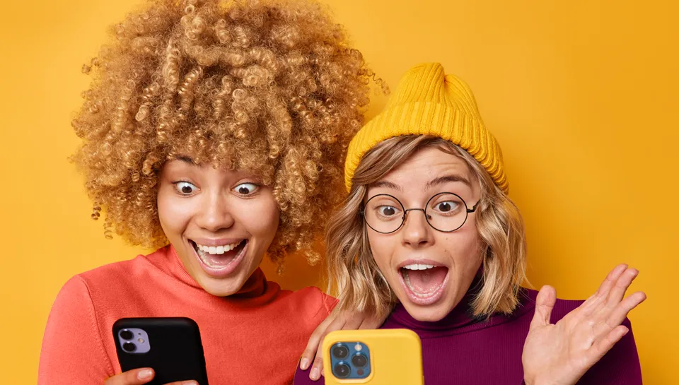 Duas moças olhando no celular animadas